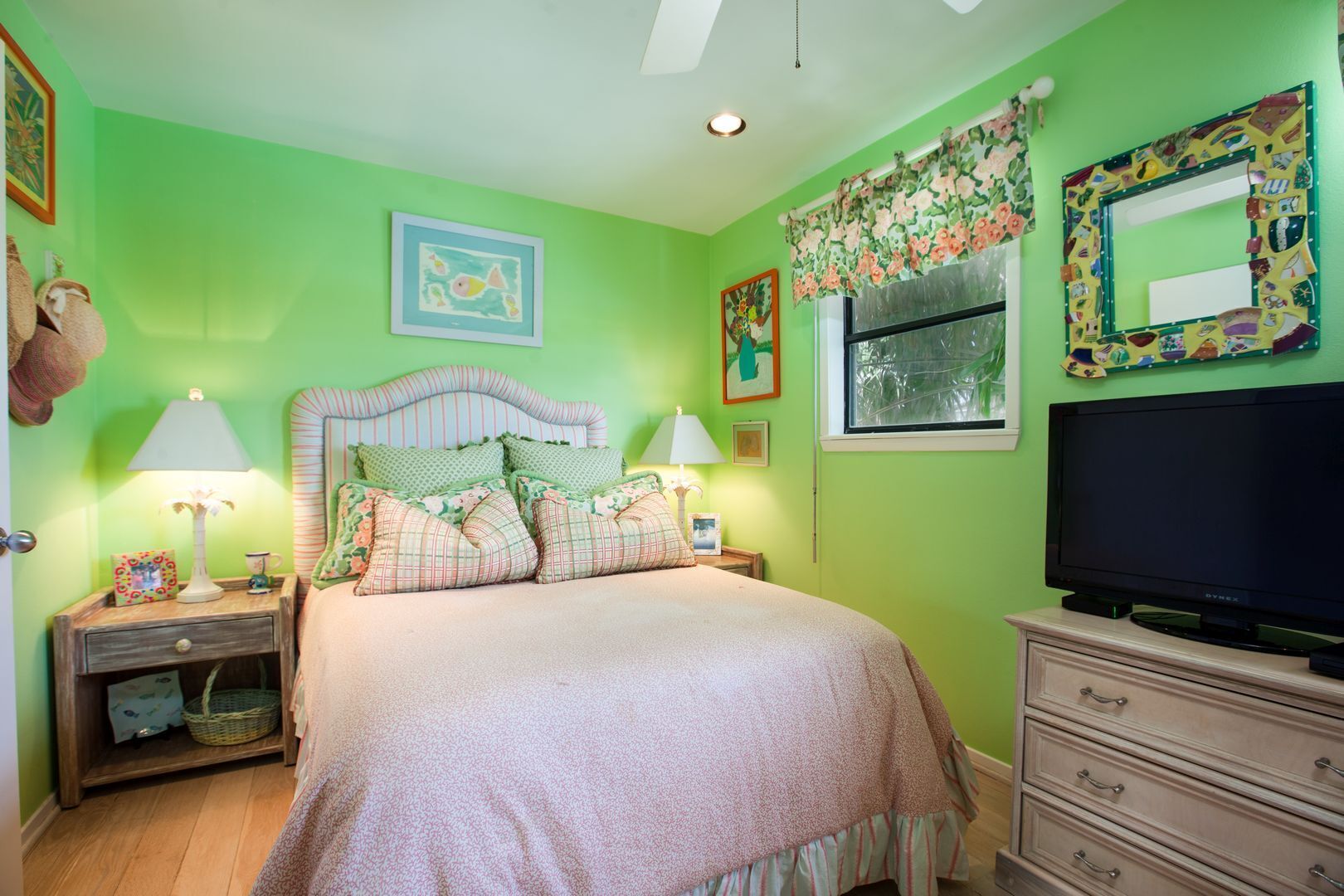 A bedroom with a bed, nightstands, lamps, a dresser, a television, and artwork on the walls.