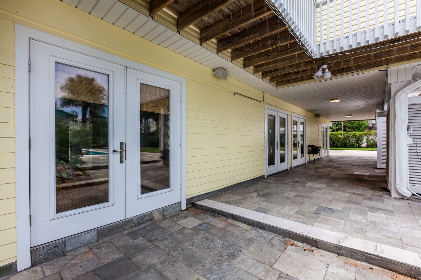 A covered patio with sliding glass doors and a stone-tiled floor.