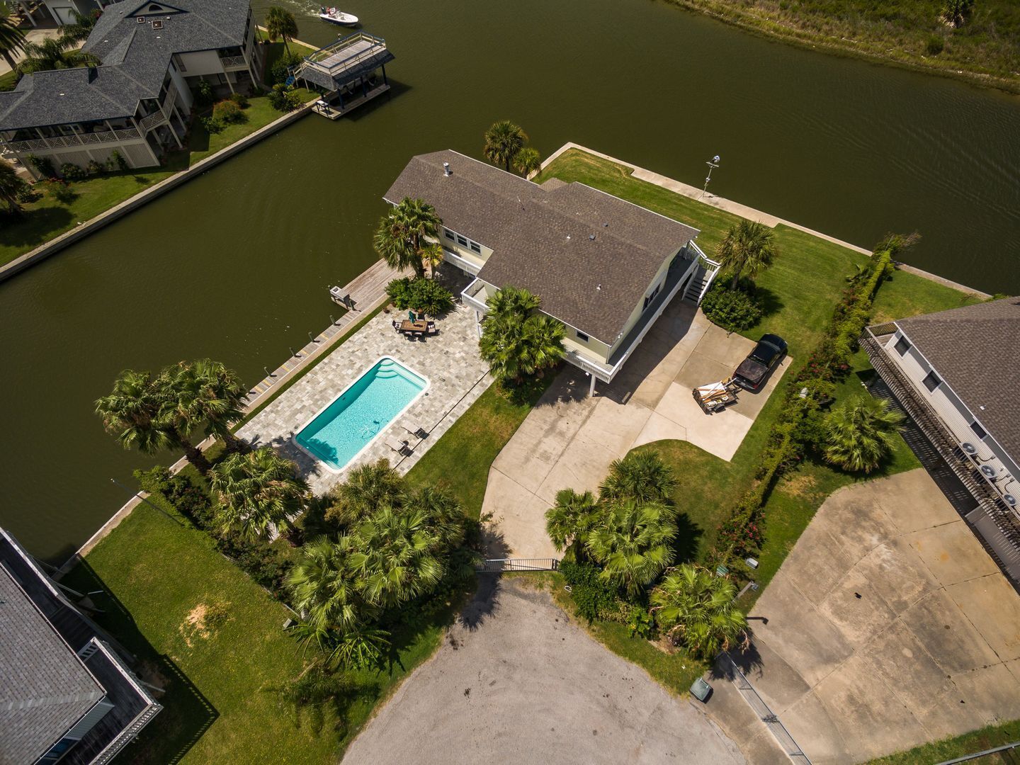 An aerial view of a residential property with a swimming pool, a dock, and a boat.