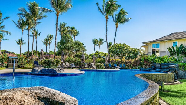 A swimming pool with a curved design, surrounded by palm trees and lounge chairs. - 🏖️Golf View Waikoloa Condo with Central AC | Walk to A-Bay & Shops (Waikoloa)