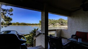 A covered outdoor area with a view of a lake, wooden deck, and outdoor furniture. - 1607 Port Villas - Gorgeous views of Braddock Cove (Hilton Head Island)