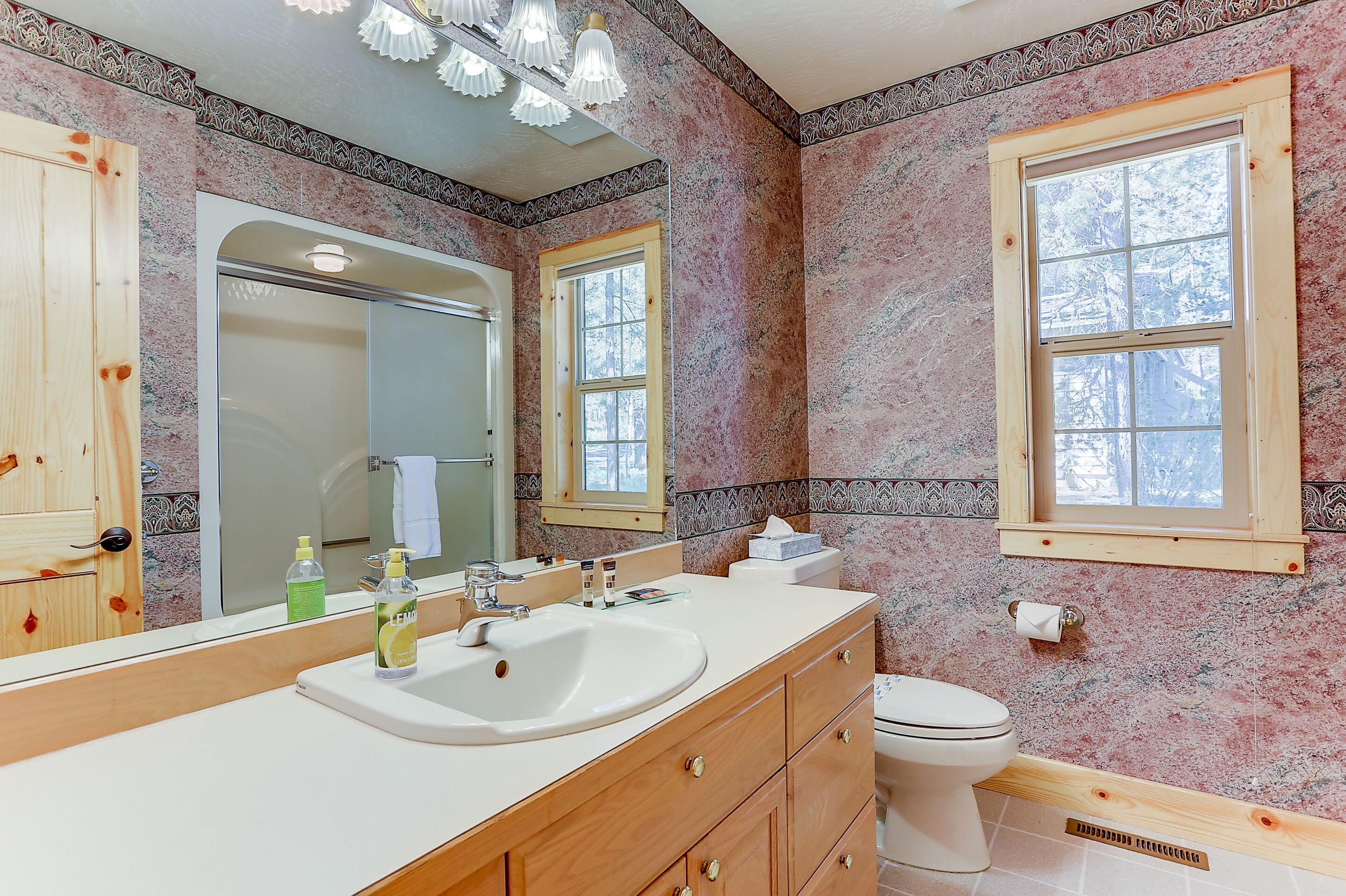 A bathroom with a wooden vanity, a sink, a mirror, and a toilet.
