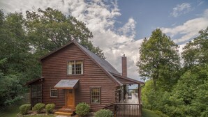 A rustic log cabin with a wooden porch, a stone pathway leading to the entrance, and a small deck with a bench. - Secluded Log Cabin on Wildlife Preserve | Mt. Mitchell Views, Game Loft & 3 Decks (Old Fort)