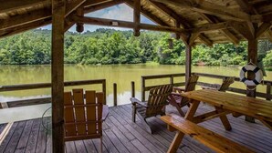 A wooden deck with picnic tables and chairs overlooking a calm lake surrounded by forest. - Secluded Log Cabin on Wildlife Preserve | Mt. Mitchell Views, Game Loft & 3 Decks (Old Fort)
