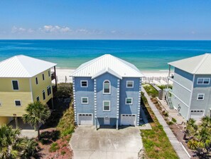 A beachfront property with three buildings, a clear view of the ocean, and a sandy beach.