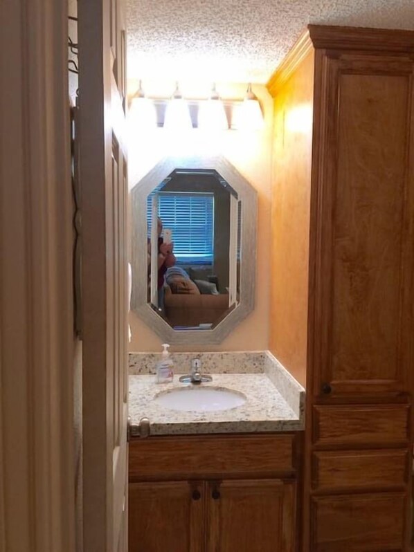 A bathroom with a vanity, a sink, and a mirror.