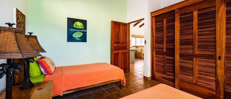 Une chambre avec deux lits, une armoire en bois, une table avec une lampe et un tableau au mur.
