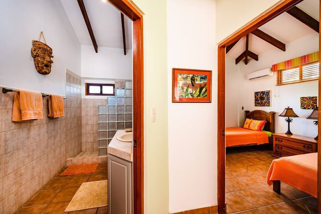 A bathroom with a shower, a toilet, and a sink. There is a towel rack with towels hanging on it.