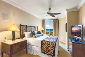 A hotel room with a bed, bedside lamps, a desk, a telephone, a television, and a ceiling fan.