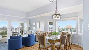 A spacious living room with a dining area, large windows, and a view of the city.