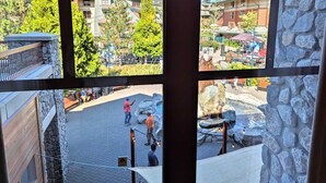 A view from a window overlooking a courtyard with stone walls, a small pool, and a seating area. - Marriott Grand Res #4256 - Next door to Heavenly Gondola - Large Studio - Gondola View (South Lake Tahoe)