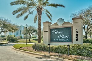 Een bordje voor Silver Shells Beach Resort & Spa met een helder uitzicht op het aangelegde gebied eromheen, inclusief palmbomen en een pad naar de ingang.
