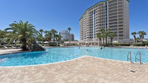 A swimming pool with palm trees and a high-rise building in the background. - St. Lucia 904 ~  9th Floor ~ Amazing Views! (Destin)