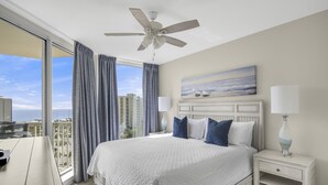 A hotel room with a large bed, a ceiling fan, a city view, and a painting on the wall. - St. Lucia 904 ~  9th Floor ~ Amazing Views! (Destin)
