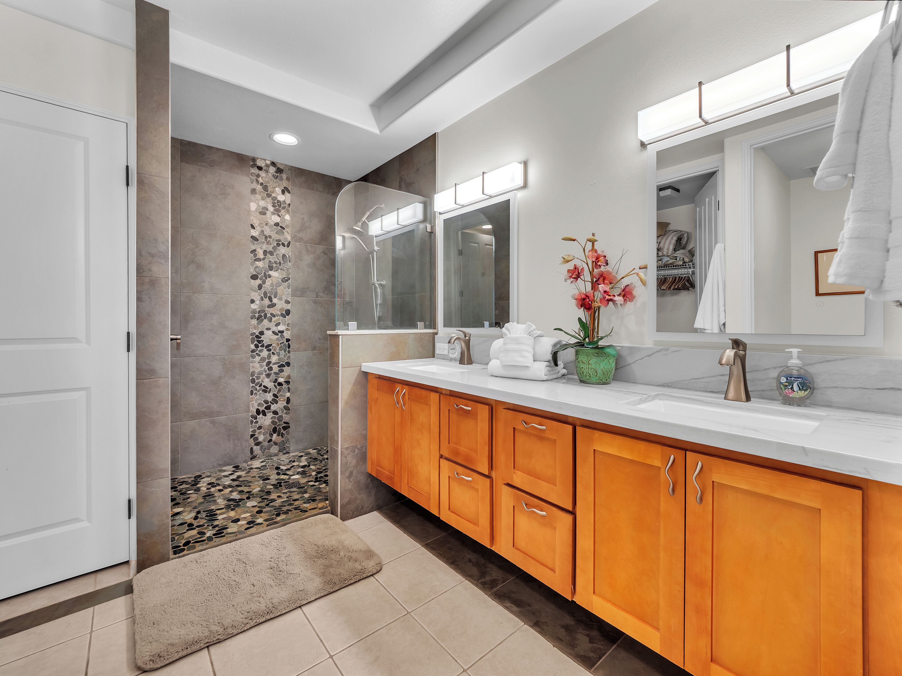 A modern bathroom with a shower, vanity, and a large mirror.