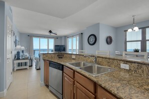 Una cocina moderna con encimeras de granito, electrodomésticos de acero inoxidable y un amplio ventanal con vistas al océano.