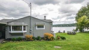 Uma casa com uma janela grande, chaminé e vista para um lago.
