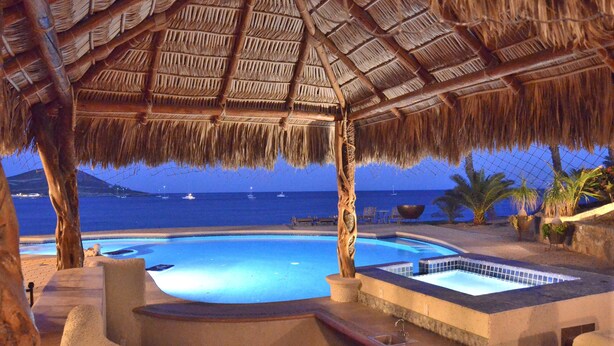 A pool area with a thatched roof, a hot tub, and a view of the sea. - Full Staff Beachfront Estate w/ 2 Villas, Pool, Tennis Court & Cook Cabo (La Paz)