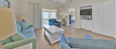 A spacious living room with a ceiling fan, a sofa, a coffee table, and a television.