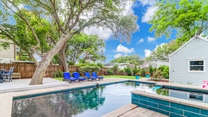 A backyard with a swimming pool, blue lounge chairs, and a wooden fence. - Backyard Oasis with Private Pool & Hot Tub! Close to Beach - 705 Carolina (Isle of Palms)