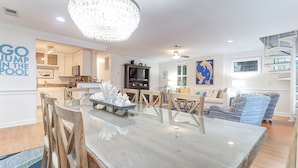 A spacious living room with a marble dining table, wooden chairs, a chandelier, and a blue-striped sofa. - Backyard Oasis with Private Pool & Hot Tub! Close to Beach - 705 Carolina (Isle of Palms)