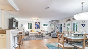 A spacious living area with a large dining table, a kitchen with white cabinets, and a cozy seating area with a sofa and chairs. - Backyard Oasis with Private Pool & Hot Tub! Close to Beach - 705 Carolina (Isle of Palms)