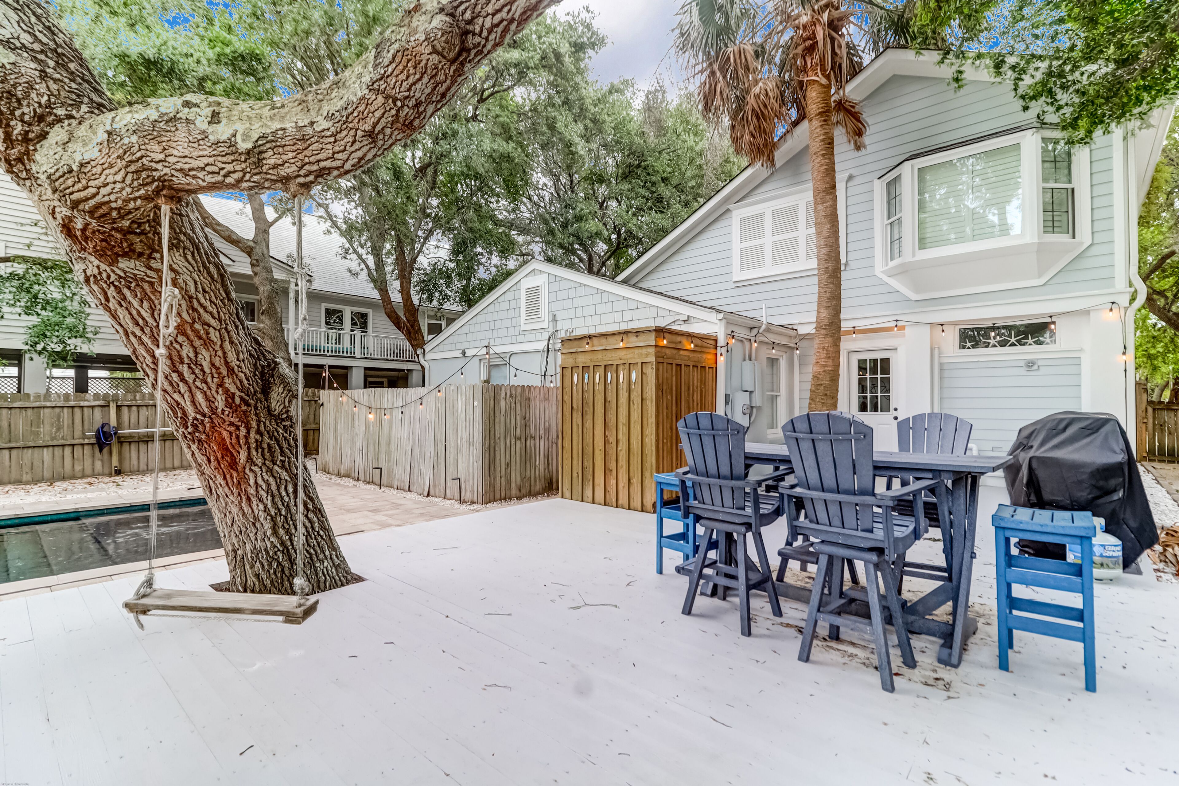A backyard with a pool, a swing, and a barbecue area.
