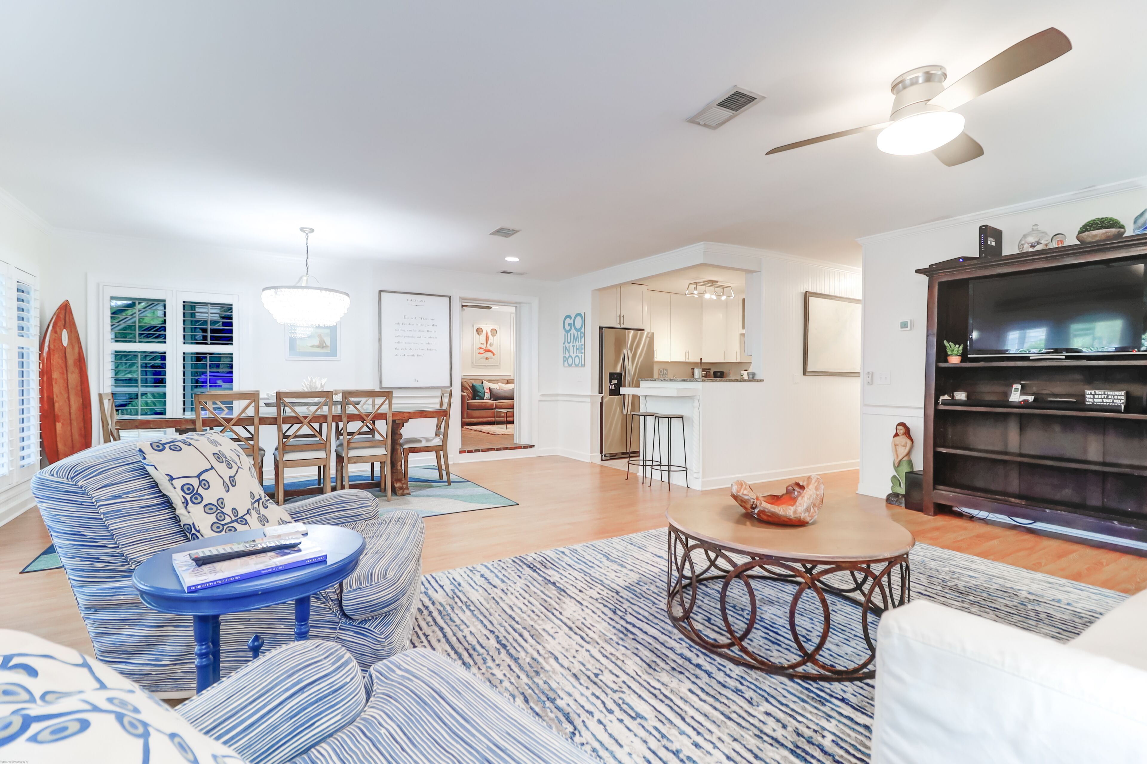 A modern living room with a sofa, coffee table, and a bookshelf. There is a dining area with a table and chairs.