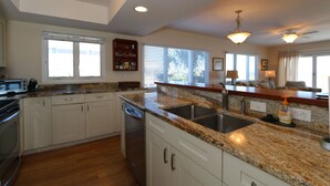 A modern kitchen with granite countertops, stainless steel appliances, and ample natural light from large windows.