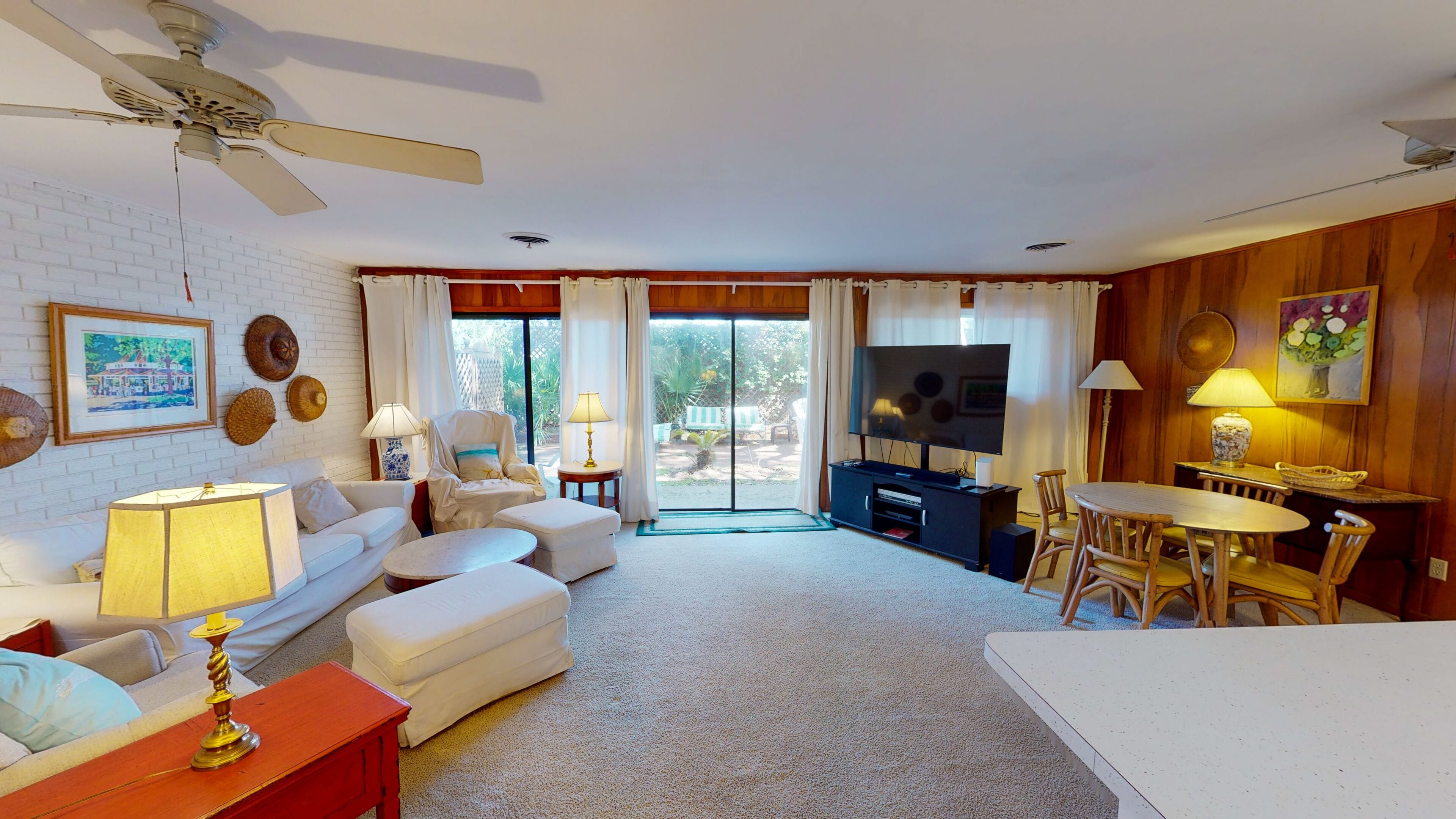 A living room with a white sofa, a coffee table, a TV, and a dining area with a table and chairs.