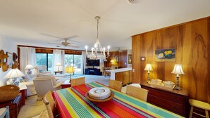 Un amplio salón con mesa de comedor, sillas, sofá y ventilador de techo.