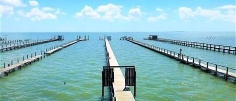 A pier extending into calm waters with a clear sky above.