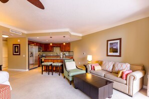 A spacious living area with a kitchen, a sofa, a coffee table, and a dining table with bar stools.