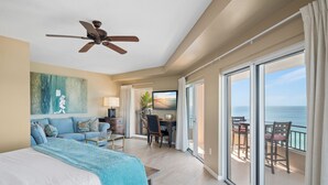 A spacious bedroom with a large bed, a ceiling fan, a desk with a chair, and a view of the ocean through large sliding doors. - Beachfront ~ Penthouse ~ 2 Balconies (Miramar Beach)