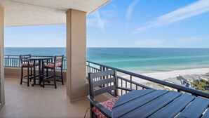 A balcony with a table and chairs, overlooking a beach and ocean. - Beachfront ~ Penthouse ~ 2 Balconies (Miramar Beach)