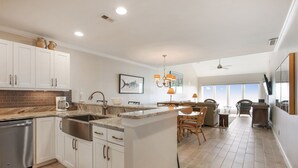 A spacious kitchen with white cabinets, a granite countertop, and a built-in island with a sink. - Shorewood 504- Ocean Front Top Floor Spectacular Views! (Hilton Head Island)