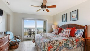 A bedroom with a bed, a dresser, a chair, a ceiling fan, and a balcony with a view. - Shorewood 504- Ocean Front Top Floor Spectacular Views! (Hilton Head Island)