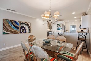 A dining area with a glass table, wicker chairs, and a chandelier.