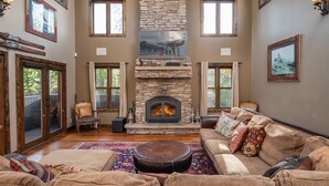 Un salón amplio con chimenea de piedra, ventanas grandes y una zona de estar acogedora.