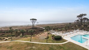 A resort with a pool, lounge chairs, and a view of the ocean. - Ocean One 120 - Beachside Condo (Hilton Head Island)