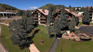 Un resort con edificios de varios pisos, un sendero pavimentado y montañas al fondo.
