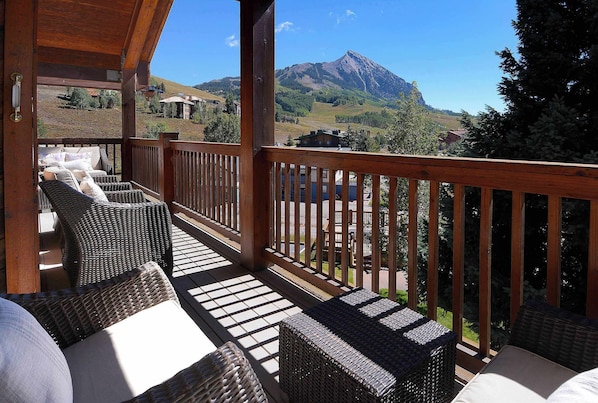 A wooden deck with wicker furniture and a view of mountains. - Southern Comfort, Gorgeous! Hot tub, Walk to base (Crested Butte)