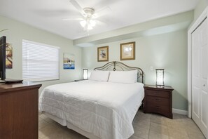 A bedroom with a bed, a desk, a nightstand, a ceiling fan, and two framed pictures on the wall. - Pelican Isle Budget Friendly 1Bd Beachfront - Free Beach Service! (Fort Walton Beach)