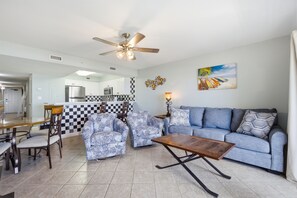 A modern living room with a sofa, armchairs, a coffee table, and a dining area with chairs and a table. - Pelican Isle Budget Friendly 1Bd Beachfront - Free Beach Service! (Fort Walton Beach)