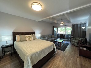 A hotel room with a large bed, a sofa, a coffee table, and a ceiling fan.
