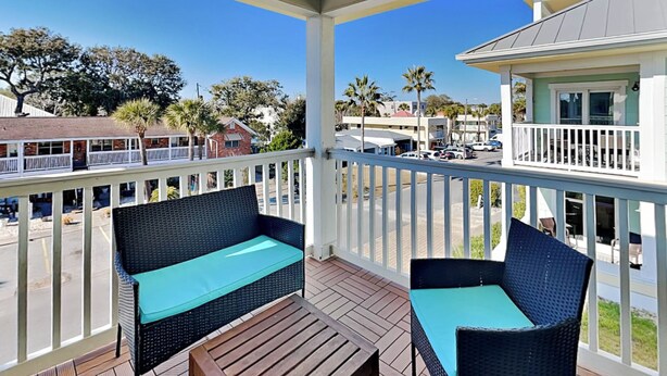 A covered outdoor area with wicker furniture and a wooden table. - Captains Watch 11 | Rooftop Pool, 1 Block to Beach (Tybee Island)