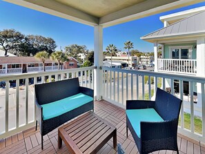 A covered outdoor area with wicker furniture and a wooden table. - Captains Watch 11 | Rooftop Pool, 1 Block to Beach (Tybee Island)