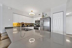 A modern kitchen with white cabinets, stainless steel appliances, and a central island with a sink.
