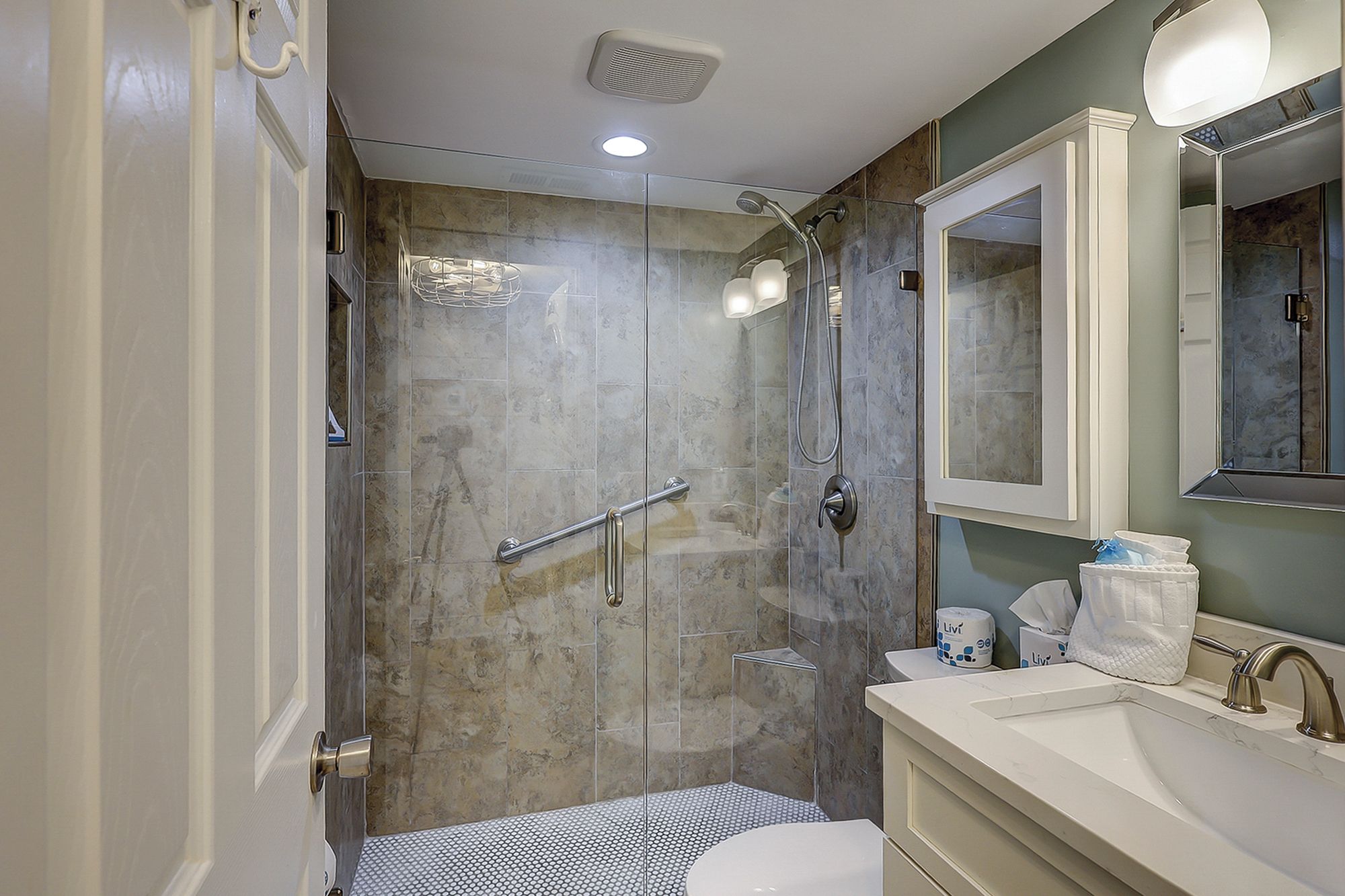 Un bagno moderno con doccia vetrata, lavandino bianco e specchio sopra.