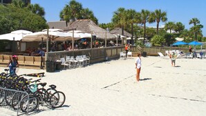 Ein Restaurant direkt am Strand mit Außenbereich, in der Nähe sind Fahrräder abgestellt und im Hintergrund Palmen.